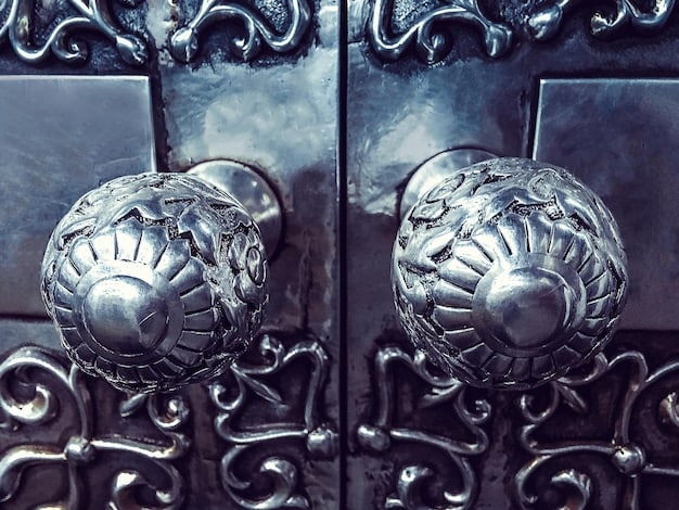 A close-up of a black front door with polished silver hardware. The door is part of a modern home with gray siding and manicured landscaping. The lighting is soft, creating a welcoming and luxurious feel.