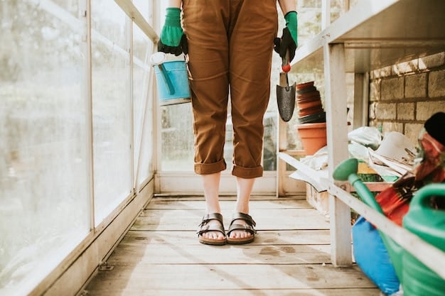 A homeowner on a ladder carefully cleaning leaves and debris from a clogged gutter using gloves and a small garden trowel, with safety glasses on. The house behind them is a typical suburban home.