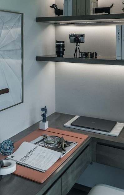 A home office featuring track lighting highlighting a desk and bookshelf. The adjustable light heads are directed to provide task lighting for the workspace.