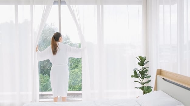 A minimalist bedroom with white walls, a large window with sheer white curtains, and light-colored wooden flooring. Sunlight streams in, creating a bright and serene atmosphere.