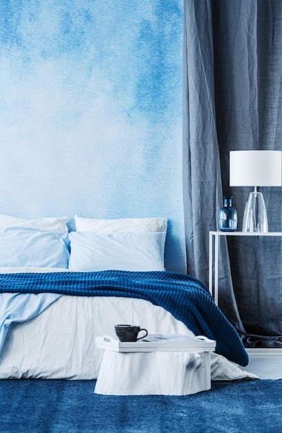 A bedroom painted in various shades of blue, from a dark navy accent wall to lighter blue bedding and accessories. The room has a calming and restful ambiance.