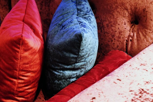 A detail shot of throw pillows on a sofa. The pillows showcase a variety of patterns, including a bold ikat print, a subtle geometric design, and a solid color. The colors are complementary, creating a cohesive yet visually interesting arrangement.