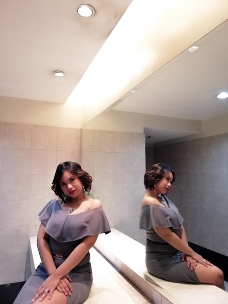 A bathroom illuminated by both recessed LED light and soft natural light, with a modern mirror enhancing the room's brightness. The overall clean ambiance suggests an open and airy feel.