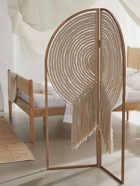 A minimalist bedroom featuring a textured headboard made of woven rattan, soft linen bedding, and a chunky knit throw blanket. The natural light enhances the textures, creating a serene and inviting atmosphere.