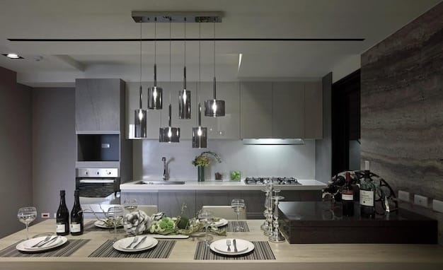 A modern kitchen featuring a combination of recessed lighting, pendant lights over the island, and under-cabinet lighting. The overall effect is bright and functional, perfect for cooking and entertaining.