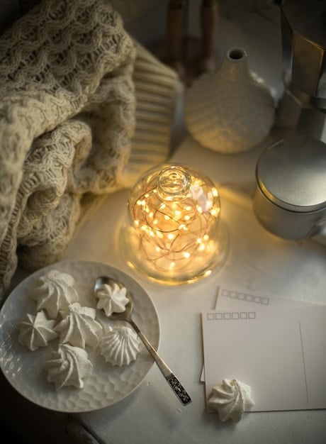 A cozy bedroom with a warm lamp on the bedside table, soft ambient lighting from a string of lights, and a dimmer switch, showcasing the importance of layered lighting.