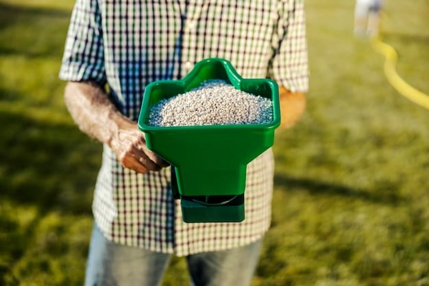 A person using a spreader to overseed a lawn. The lawn is partially green and partially bare, showing the areas that need to be filled in with new seed.