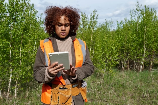 A gardener consulting the updated USDA hardiness zone map on a tablet while standing in their garden, showcasing the practical application of the map for planting decisions. The gardener is surrounded by thriving plants, emphasizing the success of using hardiness zones in gardening.